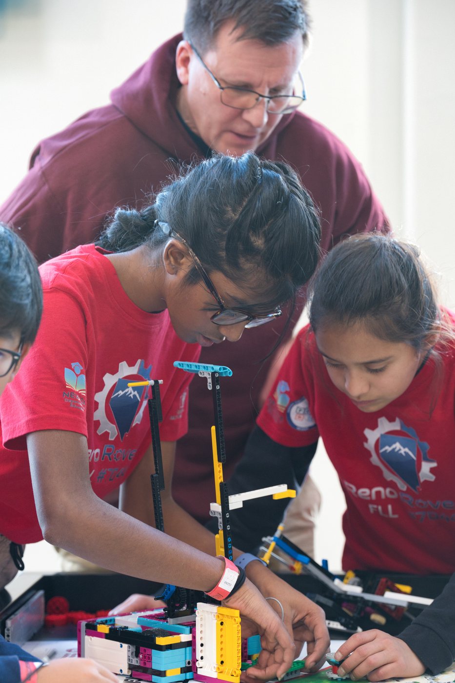 A Reno Rovers coach helping students at a robot game table