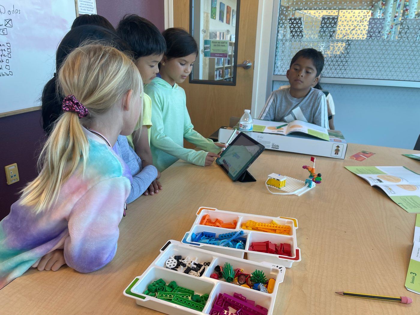 Children using a tablet and LEGO pieces during a robotics class