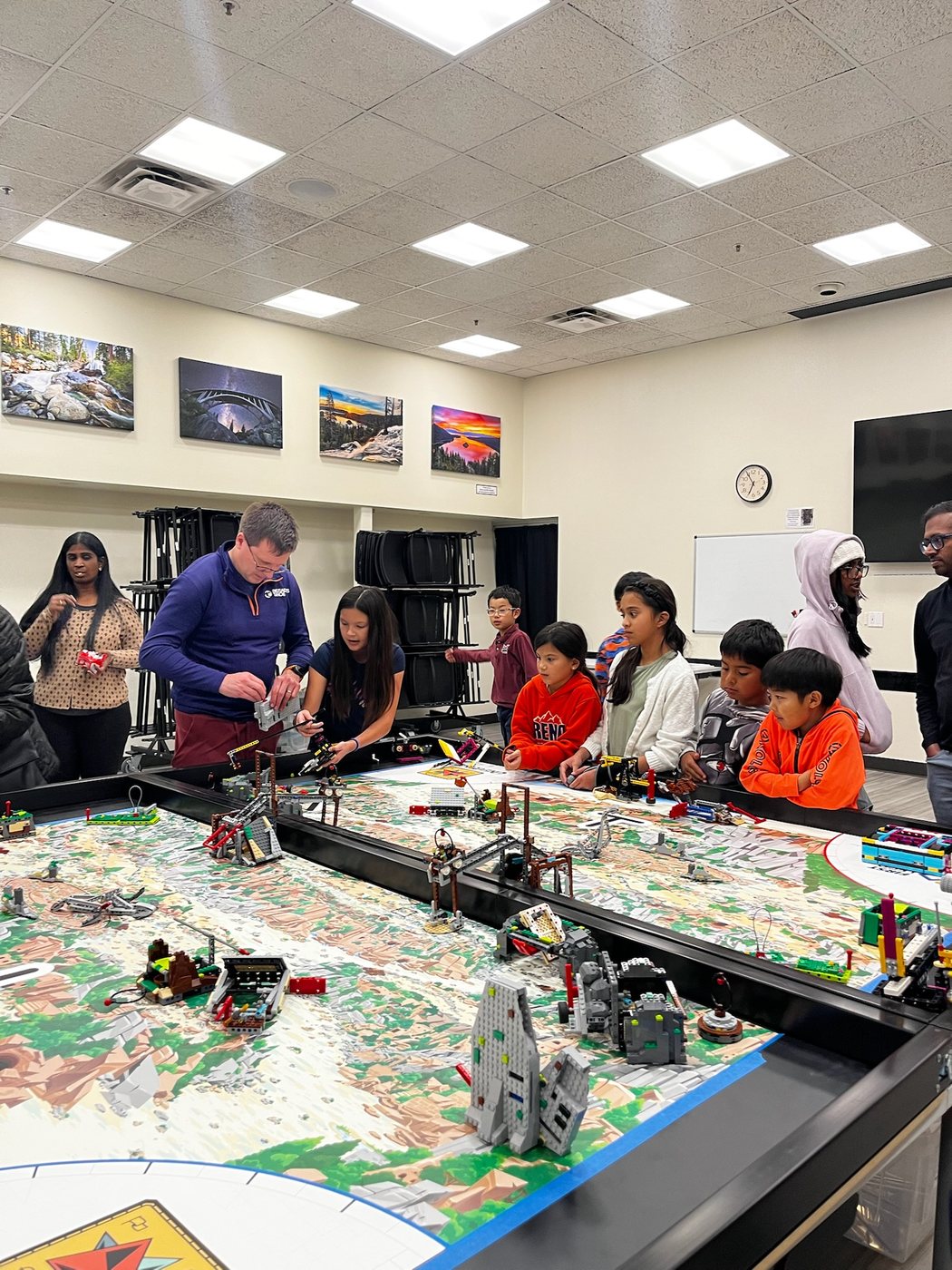 Students and coaches gathered around a robotics game table during practice